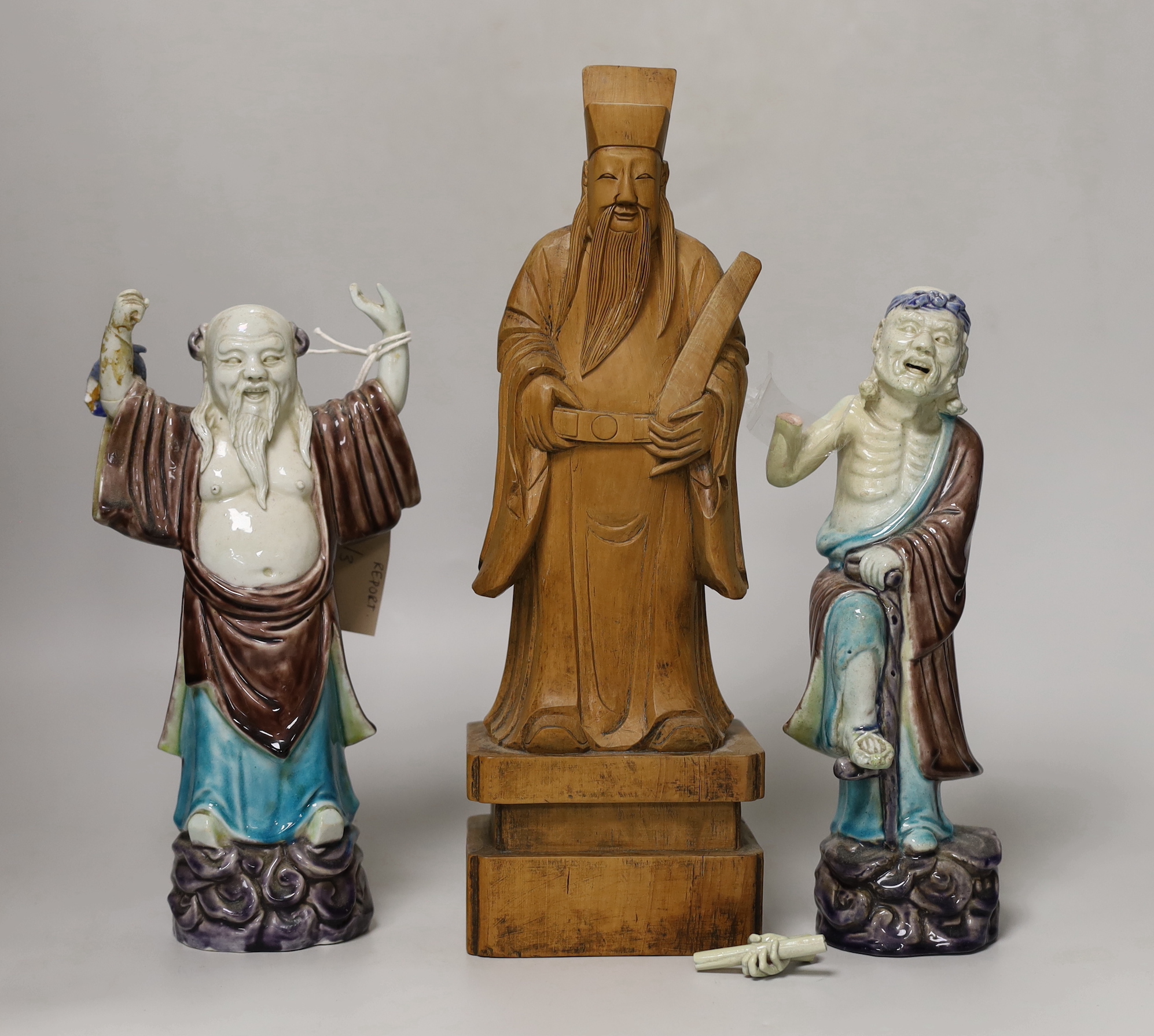 Two Chinese wucai glazed figures of immortals, Republic period, and a Chinese carved boxwood figure of an official, tallest 29cm